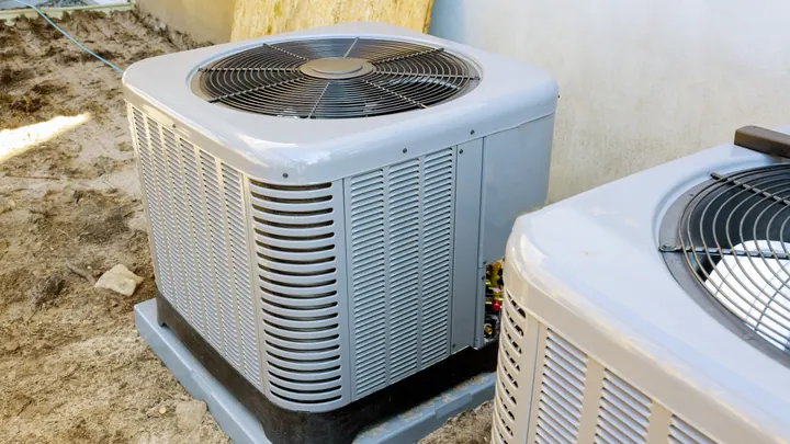 Two air conditioning condenser units standing outside a building